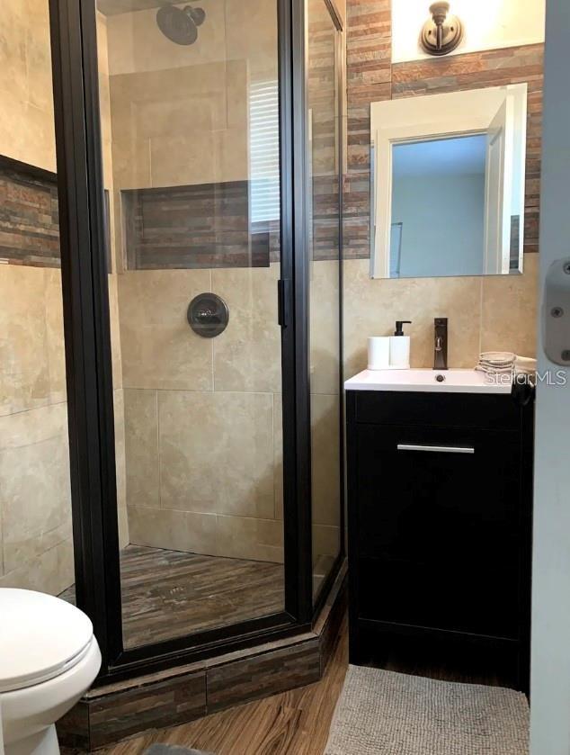 2940 Lake Margaret Dr, Orlando, FL 32806 - full bath featuring a stall shower, vanity, and tile walls