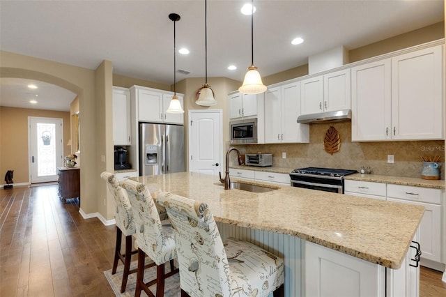 802 Soria Ln, Davenport, FL 33837 - kitchen featuring stainless steel appliances, under cabinet range hood, arched walkways, backsplash, and white cabinetry