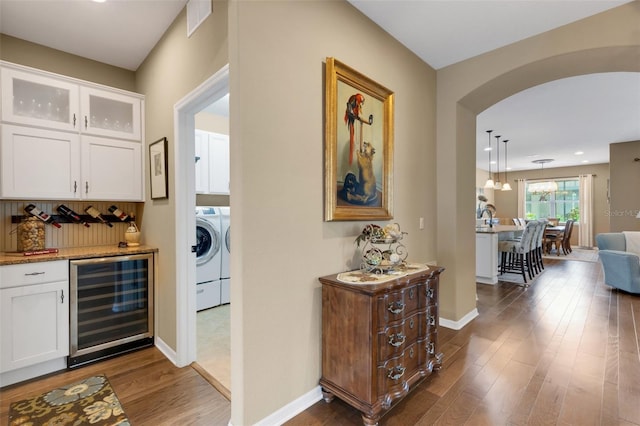802 Soria Ln, Davenport, FL 33837 - indoor dry bar with wine cooler, washer / clothes dryer, arched walkways, dark wood-style floors, and hanging light fixtures