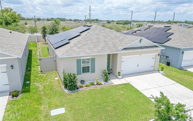 320 Boardwalk Ave, Haines City, FL 33844 - ranch-style home with stucco siding, driveway, a shingled roof, a garage, and roof mounted solar panels