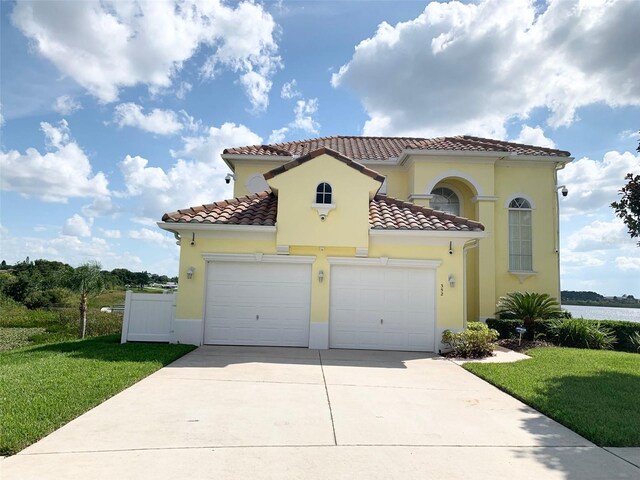 352 Cherokee Ave, Haines City, FL 33844 - mediterranean / spanish-style house with an attached garage, driveway, stucco siding, and a tiled roof