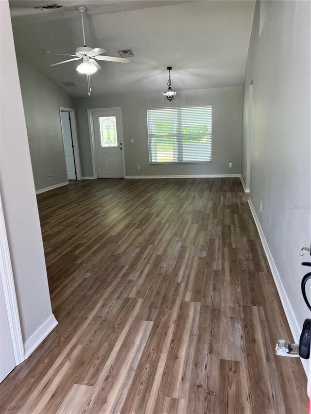 2211 Julianna Ct, Saint Cloud, FL 34769 - unfurnished living room featuring a ceiling fan, dark wood-type flooring, a chandelier, and vaulted ceiling