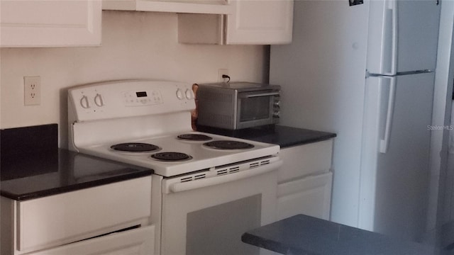 2002 Cascades Blvd Unit 207, Kissimmee, FL 34741 - kitchen featuring white appliances, white cabinets, dark countertops, and range hood