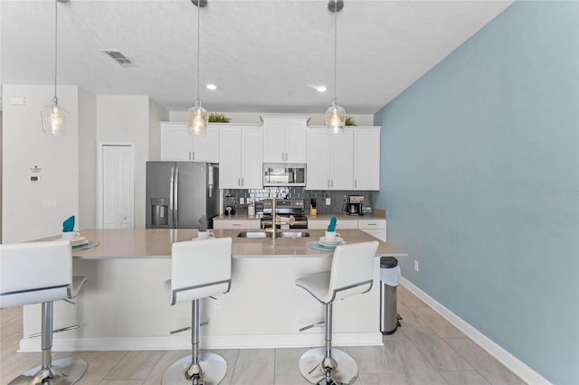 4840 Romeo Cir, Kissimmee, FL 34746 - kitchen featuring stainless steel appliances, an island with sink, backsplash, a breakfast bar area, and white cabinets