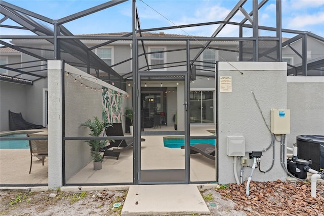 4840 Romeo Cir, Kissimmee, FL 34746 - rear view of house featuring glass enclosure, a patio, stucco siding, and an outdoor pool