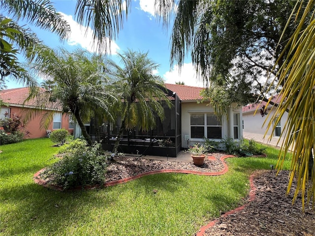 99 Auburn Dr, Kissimmee, FL 34759 - rear view of property featuring stucco siding, a lawn, a tiled roof, and a sunroom