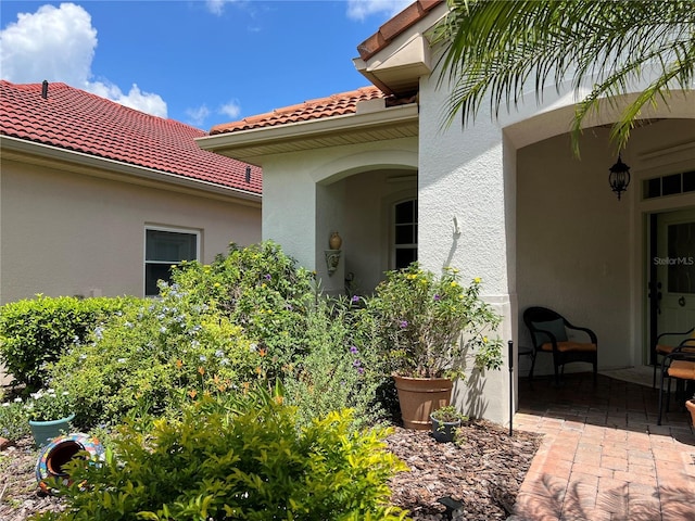 99 Auburn Dr, Kissimmee, FL 34759 - entrance to property featuring stucco siding, a tile roof, and a patio