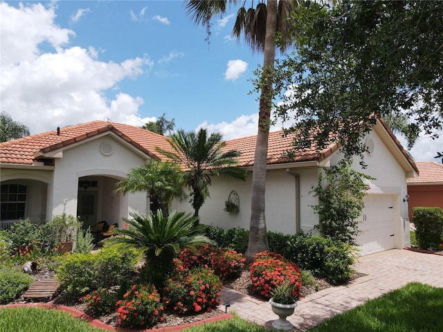 99 Auburn Dr, Kissimmee, FL 34759 - mediterranean / spanish house with a tiled roof, stucco siding, an attached garage, and driveway