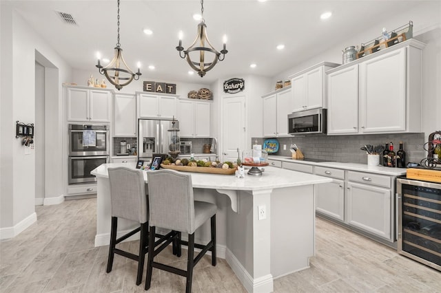 14728 Scott Key Dr, Winter Garden, FL 34787 - kitchen featuring wine cooler, stainless steel appliances, a chandelier, an island with sink, and backsplash