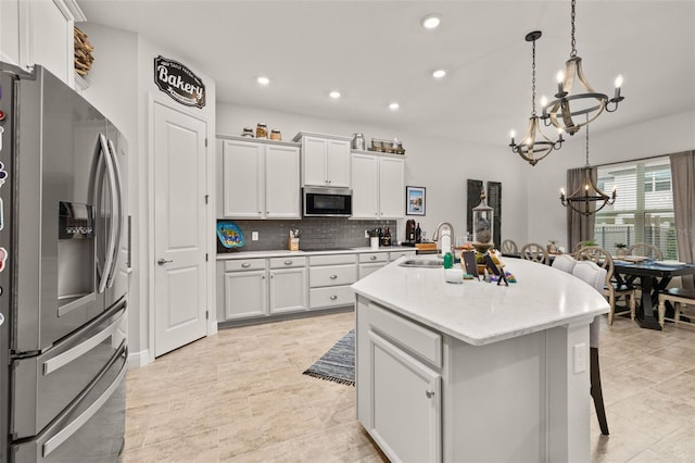 14728 Scott Key Dr, Winter Garden, FL 34787 - kitchen with stainless steel appliances, a chandelier, light countertops, white cabinets, and decorative backsplash
