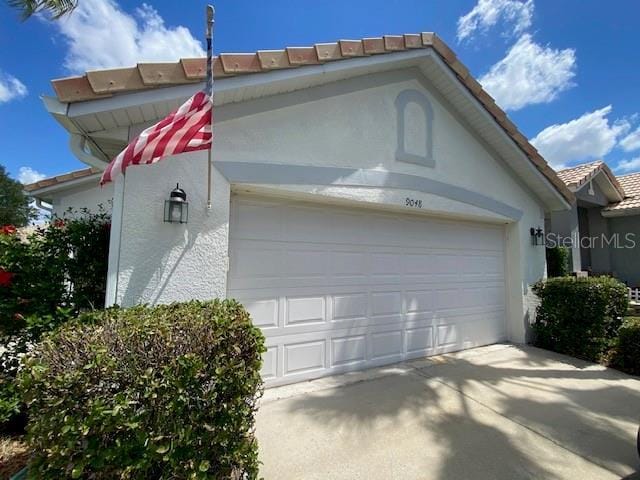 9048 Saint Andrews Way, Mount Dora, FL 32757 - view of side of home with stucco siding, a tiled roof, and concrete driveway