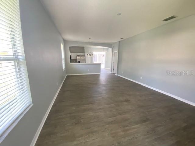 9048 Saint Andrews Way, Mount Dora, FL 32757 - unfurnished living room with dark wood finished floors, arched walkways, and a chandelier