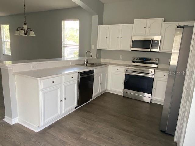 9048 Saint Andrews Way, Mount Dora, FL 32757 - kitchen featuring appliances with stainless steel finishes, a peninsula, a chandelier, dark wood-style floors, and white cabinetry