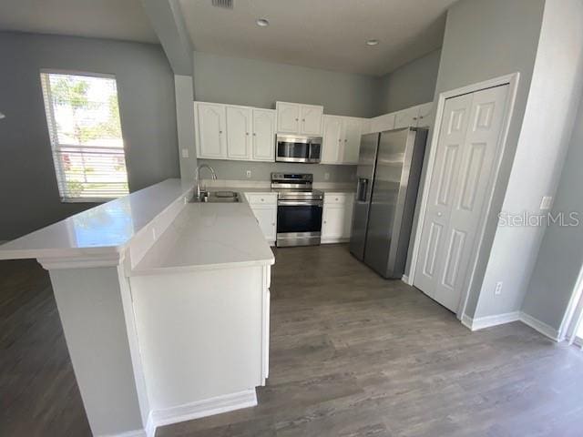 9048 Saint Andrews Way, Mount Dora, FL 32757 - kitchen featuring appliances with stainless steel finishes, a peninsula, light countertops, wood finished floors, and white cabinetry