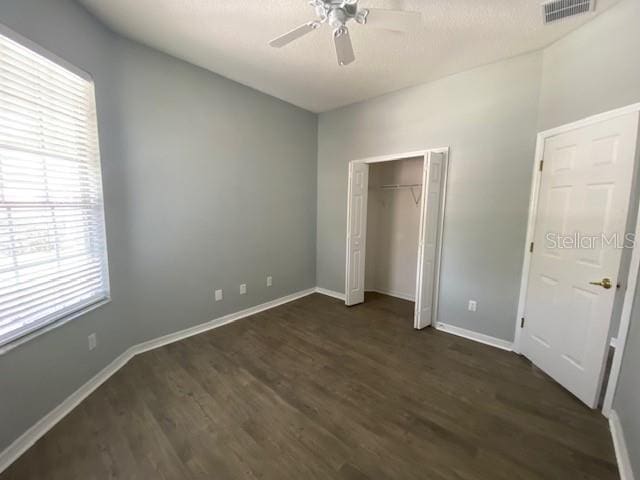 9048 Saint Andrews Way, Mount Dora, FL 32757 - unfurnished bedroom with multiple windows, dark wood-style flooring, a closet, and a ceiling fan