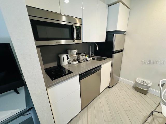 3100 Parkway Blvd Unit 316, Kissimmee, FL 34747 - kitchen featuring stainless steel appliances, white cabinets, modern cabinets, light countertops, and light wood-type flooring