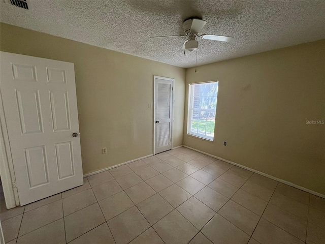 3828 Bowline Cir Unit 101, Kissimmee, FL 34741 - unfurnished bedroom with light tile patterned floors, a closet, a textured ceiling, and ceiling fan