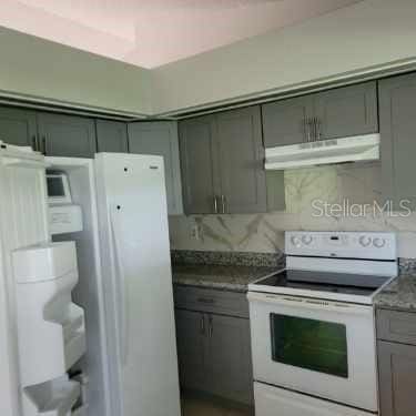 621 N Delmonte Ct, Kissimmee, FL 34758 - kitchen featuring white appliances, under cabinet range hood, gray cabinetry, and backsplash