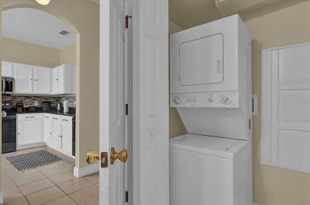 2234 Calabria Ave, Davenport, FL 33897 - laundry area featuring stacked washer / dryer, light tile patterned floors, and arched walkways