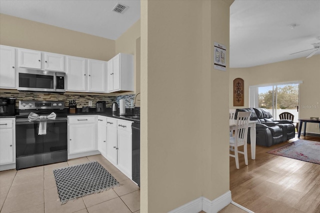 2234 Calabria Ave, Davenport, FL 33897 - kitchen with appliances with stainless steel finishes, dark countertops, open floor plan, decorative backsplash, and white cabinets