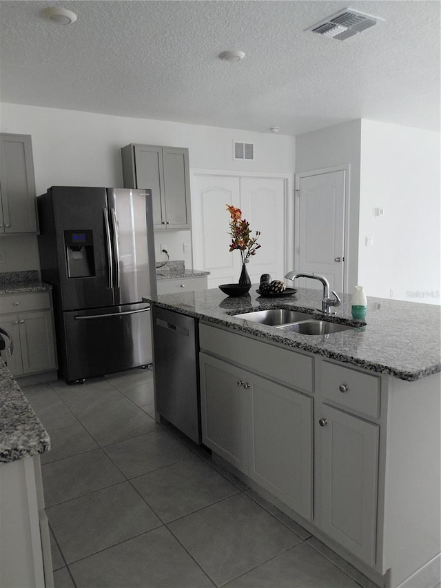 2132 Desert Rose Dr, Davenport, FL 33837 - kitchen featuring appliances with stainless steel finishes, a textured ceiling, light stone counters, light tile patterned flooring, and a kitchen island with sink