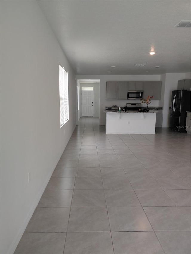 2132 Desert Rose Dr, Davenport, FL 33837 - kitchen with black refrigerator with ice dispenser, stainless steel microwave, gray cabinets, light tile patterned floors, and a kitchen island with sink