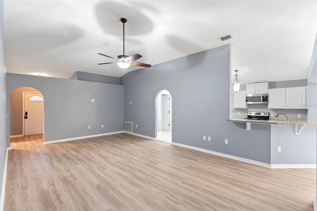 2126 Wekiva Reserve Blvd, Apopka, FL 32703 - unfurnished living room with arched walkways, ceiling fan, lofted ceiling, and light wood finished floors