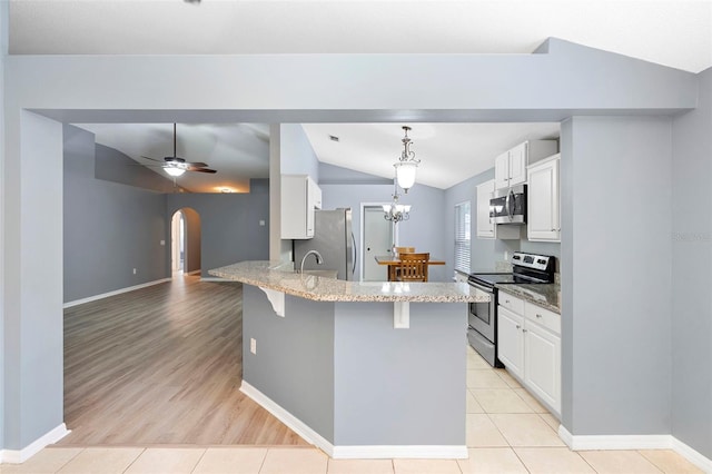 2126 Wekiva Reserve Blvd, Apopka, FL 32703 - kitchen with stainless steel appliances, vaulted ceiling, light stone countertops, arched walkways, and a breakfast bar area