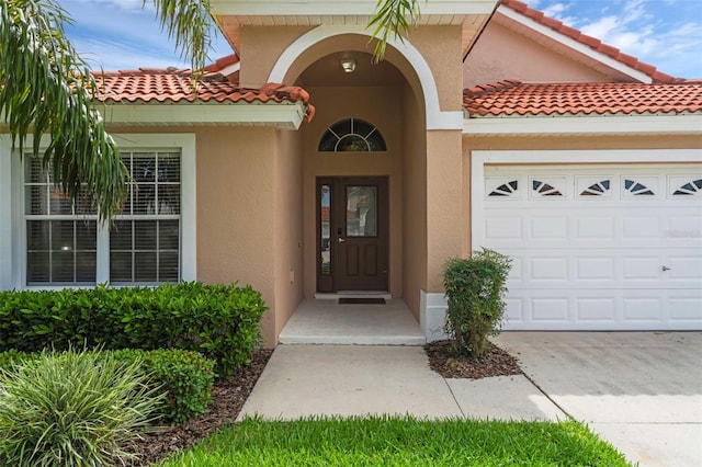 242 Saragossa Ave, Davenport, FL 33897 - view of exterior entry with a tile roof, stucco siding, a garage, and driveway