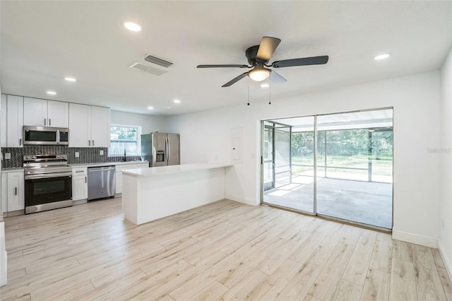 4212 Harry Dr, Fruitland Park, FL 34731 - kitchen featuring stainless steel appliances, a peninsula, tasteful backsplash, light wood-style floors, and a ceiling fan