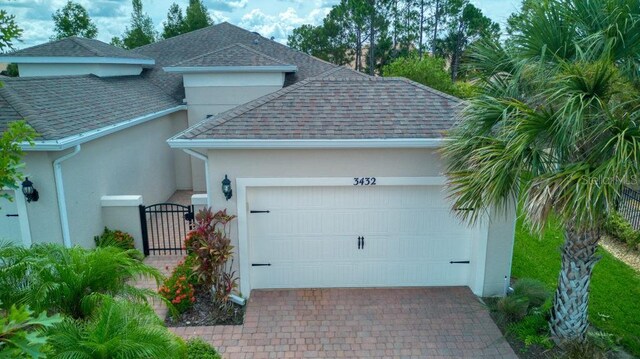 3432 Fallbrook Dr, Poinciana, FL 34759 - garage featuring decorative driveway and a gate