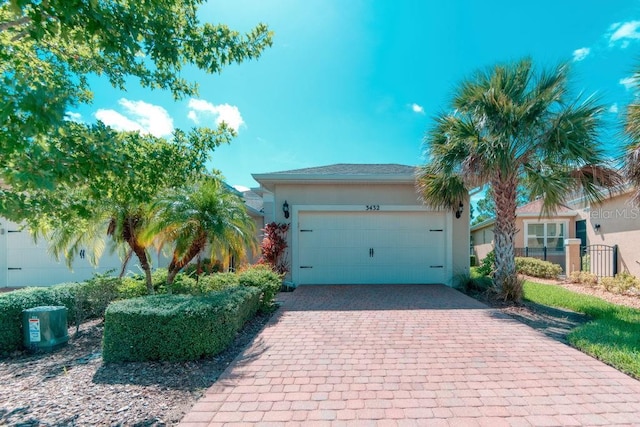 3432 Fallbrook Dr, Poinciana, FL 34759 - view of front of house featuring stucco siding, decorative driveway, and an attached garage