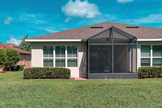 3432 Fallbrook Dr, Poinciana, FL 34759 - rear view of house featuring a lawn, stucco siding, glass enclosure, and a shingled roof