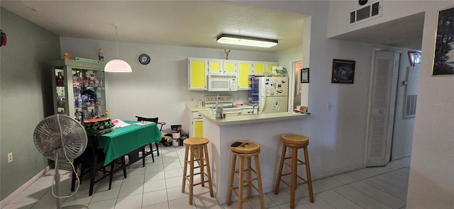 5291 Images Cir Unit 302, Kissimmee, FL 34746 - kitchen featuring white appliances, a peninsula, a kitchen breakfast bar, pendant lighting, and light tile patterned floors