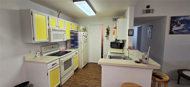 5291 Images Cir Unit 302, Kissimmee, FL 34746 - kitchen featuring white appliances, a peninsula, light countertops, dark wood-type flooring, and a kitchen breakfast bar