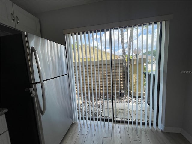 12161 Sandal Creek Way, Orlando, FL 32824 - detailed view of freestanding refrigerator, light wood-type flooring, and white cabinets
