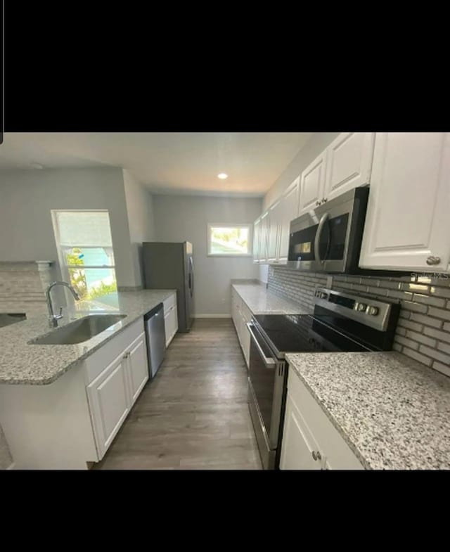838 E Lime St, Lakeland, FL 33801 - kitchen with stainless steel appliances, backsplash, light wood-style flooring, white cabinets, and light stone countertops