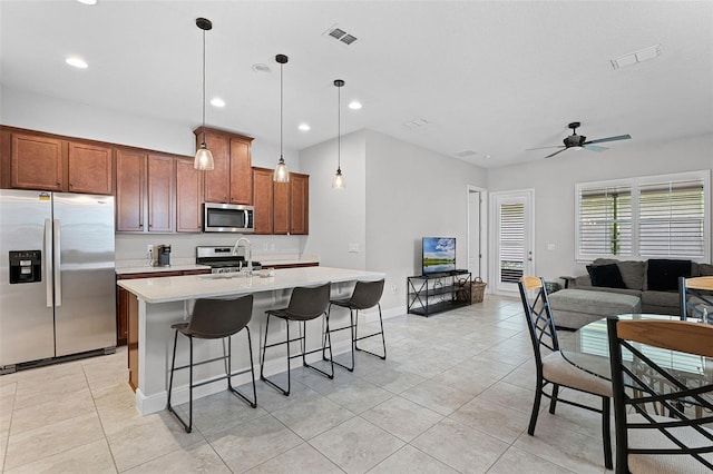 2419 Datura Loop, Saint Cloud, FL 34772 - kitchen with stainless steel appliances, light tile patterned floors, light countertops, a kitchen breakfast bar, and a kitchen island with sink