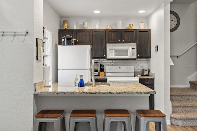 2602 Lodi Cir Unit 107, Kissimmee, FL 34746 - kitchen with white appliances, dark brown cabinets, a breakfast bar area, a peninsula, and a textured wall