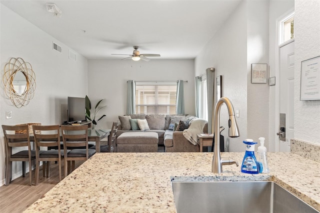 2602 Lodi Cir Unit 107, Kissimmee, FL 34746 - kitchen with wood finished floors, a ceiling fan, and light stone counters