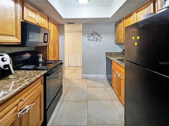 4755 S Texas Ave Unit 4755D, Orlando, FL 32839 - kitchen with black appliances, a tray ceiling, light stone countertops, light tile patterned flooring, and brown cabinetry