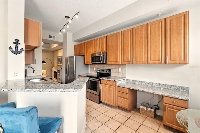 501 Mirasol Cir Unit 213, Celebration, FL 34747 - kitchen featuring stainless steel appliances, light tile patterned floors, decorative backsplash, a peninsula, and light stone countertops