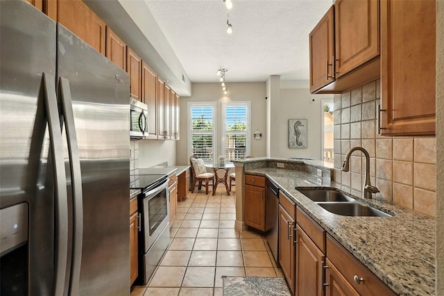 501 Mirasol Cir Unit 213, Celebration, FL 34747 - kitchen featuring stainless steel appliances, brown cabinets, tasteful backsplash, light stone counters, and a textured ceiling