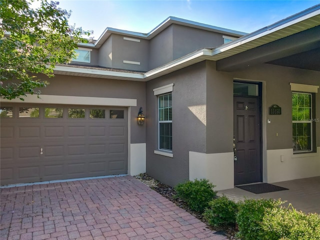15150 Evergreen Oak Loop, Winter Garden, FL 34787 - entrance to property featuring stucco siding, a garage, and decorative driveway