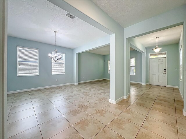 15150 Evergreen Oak Loop, Winter Garden, FL 34787 - empty room featuring light tile patterned floors, a textured ceiling, a chandelier, and healthy amount of natural light