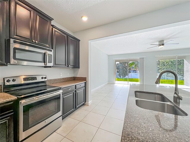 15150 Evergreen Oak Loop, Winter Garden, FL 34787 - kitchen with appliances with stainless steel finishes, a textured ceiling, light tile patterned floors, a ceiling fan, and dark stone counters
