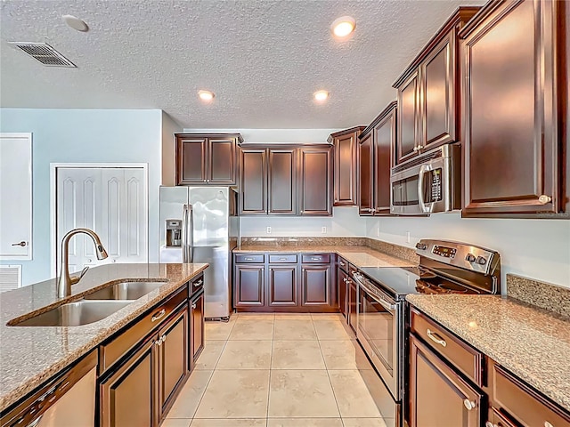 15150 Evergreen Oak Loop, Winter Garden, FL 34787 - kitchen with stainless steel appliances, dark stone counters, a textured ceiling, light tile patterned floors, and recessed lighting