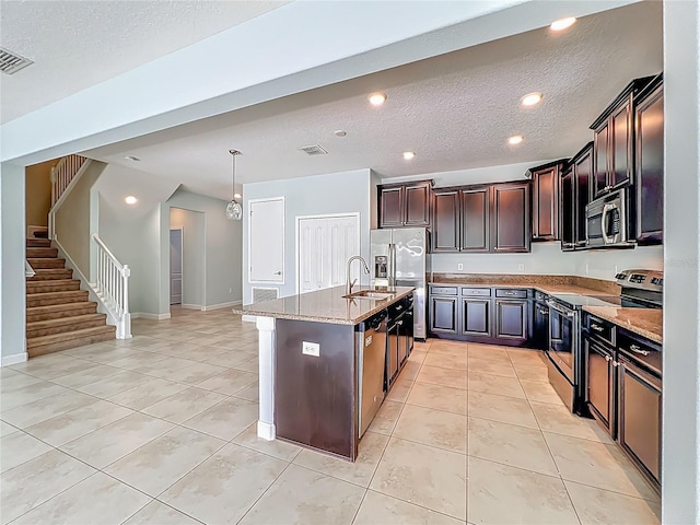 15150 Evergreen Oak Loop, Winter Garden, FL 34787 - kitchen featuring appliances with stainless steel finishes, light tile patterned floors, light stone countertops, a kitchen island with sink, and a textured ceiling