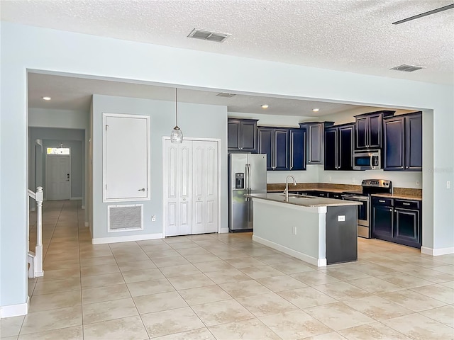 15150 Evergreen Oak Loop, Winter Garden, FL 34787 - kitchen featuring stainless steel appliances, light tile patterned floors, an island with sink, a textured ceiling, and recessed lighting