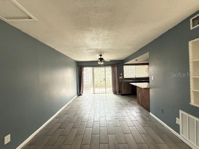 5423 Brookswood Way Unit 801, Orlando, FL 32808 - unfurnished living room with a textured ceiling, ceiling fan, and dark wood finished floors